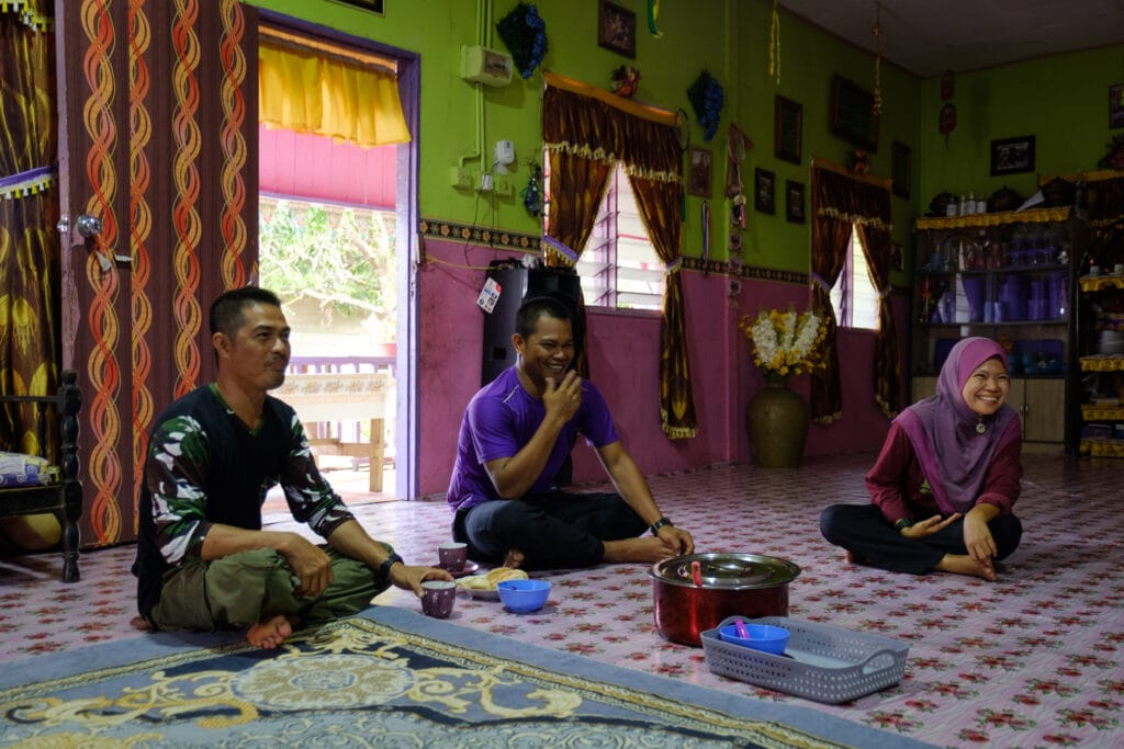 Runji Ramsa, Mohd Azril Putrah, and Andrapidah Putrah enjoy afternoon tea together in their extended family home in Dagat.