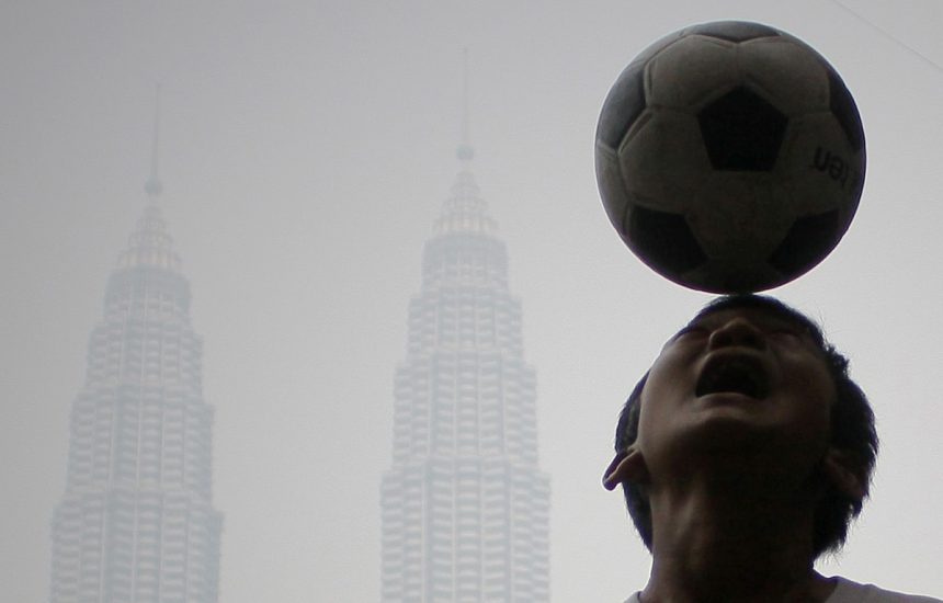 A boy playing a football during haze strikes Malaysia's landmark Petronas Twin Towers in Kuala Lumpur 15 Jun 2013. PIX Firdaus Latif